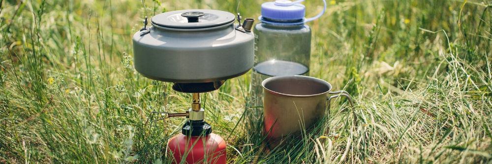 camping-stove-beside-water-bottle-in-grass
