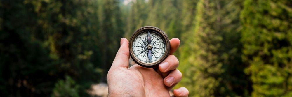 person holding compass while hiking